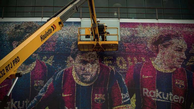 Trabajadores retiran la imagen de Messi de la fachada del Camp Nou. FOTO: EUROPA PRESS