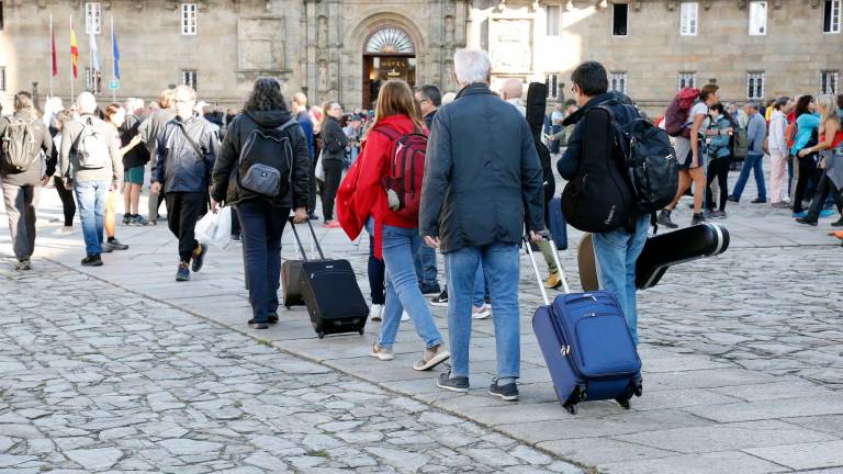 Turistas con maletas en la plaza del Obradoiro, de camino o tras abandonar algún alojamiento. Foto: Antonio Hernández