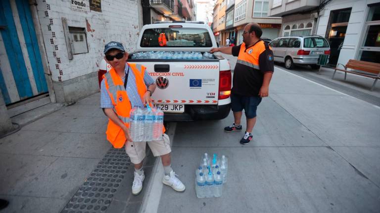 Voluntarios de Protección Civil repartindo auga embotellada á veciñanza. Foto: Concello de Malpica