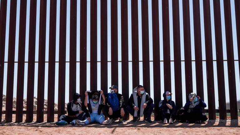 Los migrantes que buscan asilo se entregan a la Patrulla Fronteriza de Estados Unidos en el Muro fronterizo con México. FOTO: Allison Dinner