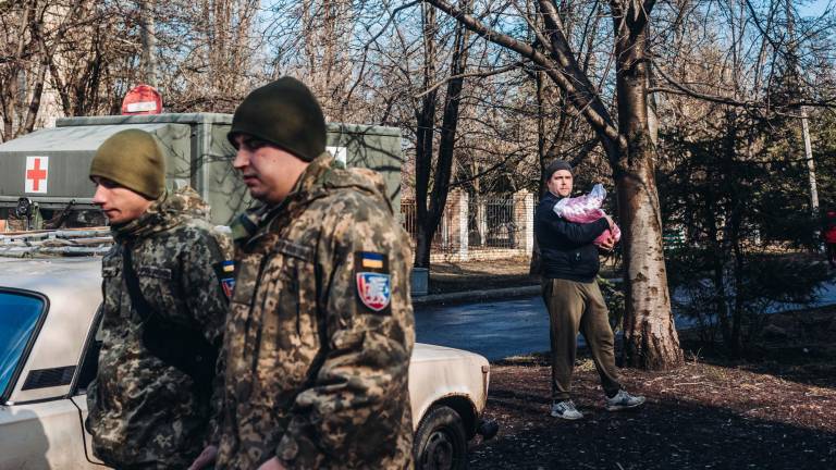 Unos soldados del ejército ucraniano caminan frente a un padre y su bebe. FOTO: Diego Herrera / Europa Press 23/02/2022