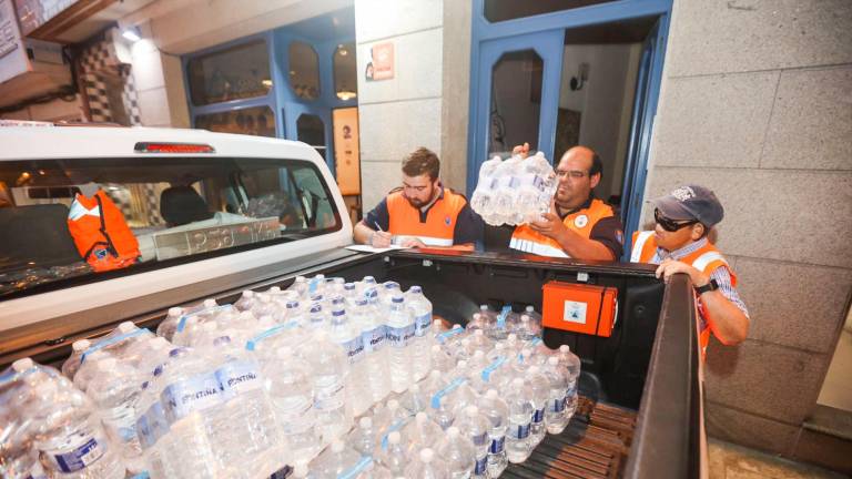 Personal de la agrupación de Protección Civil de Malpica se dispone a repartir botellas de agua entre los vecinos de la localidad. Foto: C.M.