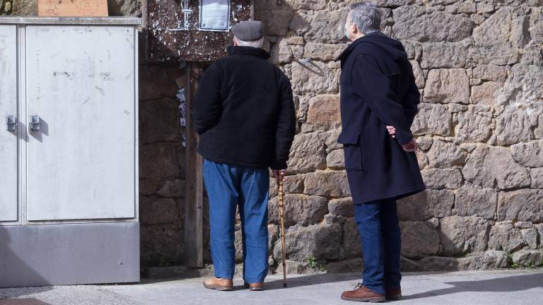 En la imagen de archivo, dos hombres leen una esquela en una calle del municipio gallego de Guitiriz, en Lugo. CARLOS CASTRO/EUROPA PRESS