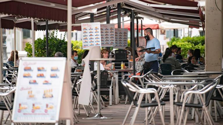 Un camarero atiende una mesa en la terraza de una cafetería