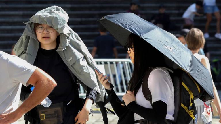 valores extremos. Dos peregrinas protegiéndose este domingo del calor mientras hacían cola para entrar en la Catedral de Santiago. Foto: Xoán Rey / EFE