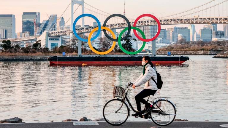 EXPECTACIÓN Una ciclista paseando ante los aros olímpicos en Tokio. Foto: Viola Kam