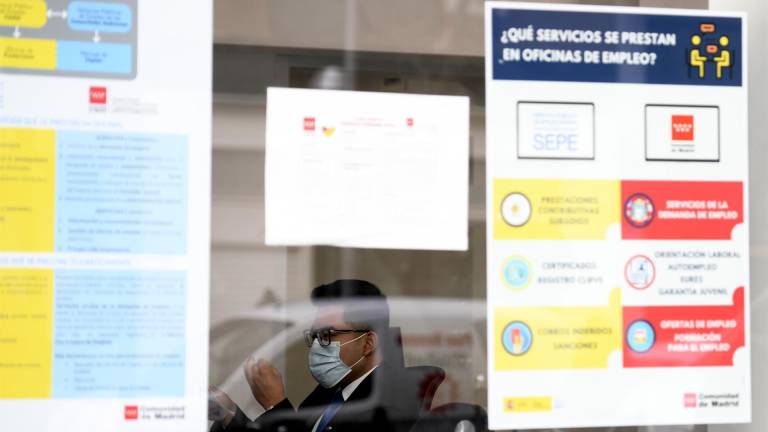 Un hombre con mascarilla tras el cristal de la puerta de una oficina de empleo, SEPE. ÓSCAR CAÑAS/EUROPA PRESS