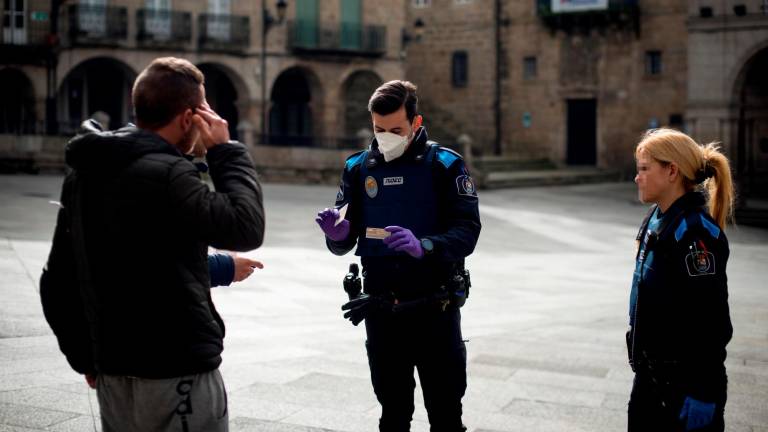 Un agente de la Policía identifica a dos ciudadanos en Ourense, durante los primeros días del confinamiento (Foto: Brais Lorenzo)