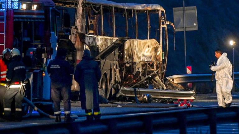 Bosnek (Bulgaria), 23/11/2021.- Bomberos, policías e investigadores inspeccionan los restos del autobús calcinado. VASSIL DONEV / EFE