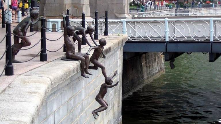 <b>La Gente del Río</b>. El escultor Chong Fah Cheong elaboró este grupo escultórico de bronce en el que un grupo de niños felices se disponen a saltar en el río Singapur. (Fuente, hive.news)