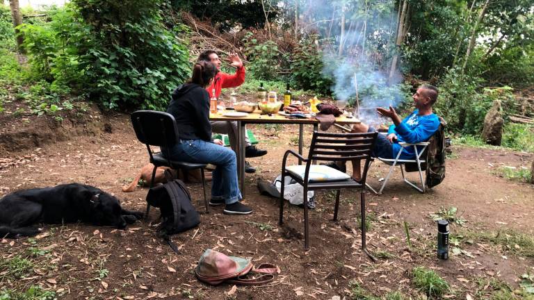 asadito. Fernando (de azul) conversa con sus invitados, una mujer y otro hombre, que preparan una churrascada y escuchan música (Santiago). Foto: ECG