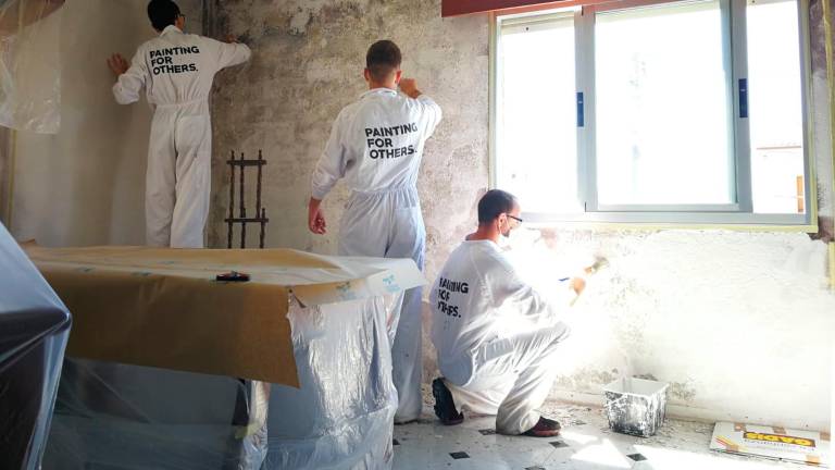 COOPERACIÓN INTERNACIONAL es la ONG que está detrás de ‘Painting for Others’. En la foto, Juan Pablo, Rafa y Jorge pintan una de las paredes más afectadas de la casa situada en el Castiñeiriño. Foto: ONG