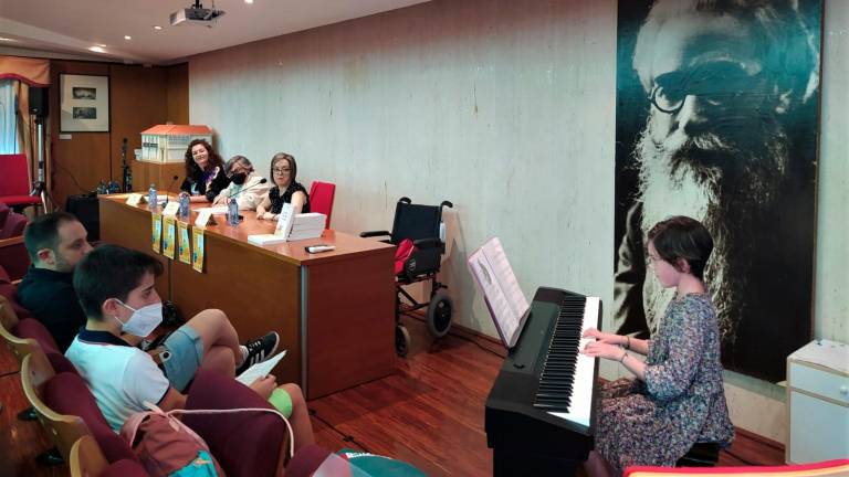 ACTO MUSICAL. Unha alumna da Escola de Música da Pobra tocando o piano na presentación do libro; na mesa, pola equerda, Patrica Lojo, Cristina Andrade e Laura Novelle. F: C.