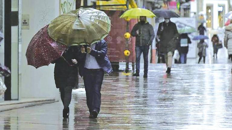 vuelven las lluvias. Personas caminando por una calle de A Coruña protegidas de la lluvia con un paraguas, imagen que se repetirá este jueves con la llegada de una borrasca a Galicia. Foto: M.Dylan / E.press.