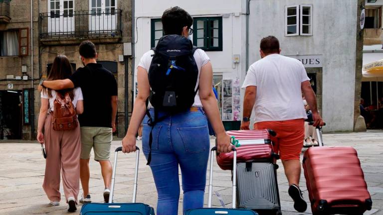 Turistas entrando con maletas en el casco histórico compostelano camino de algún hotel o piso vacacional. Foto: Fernando Blanco 