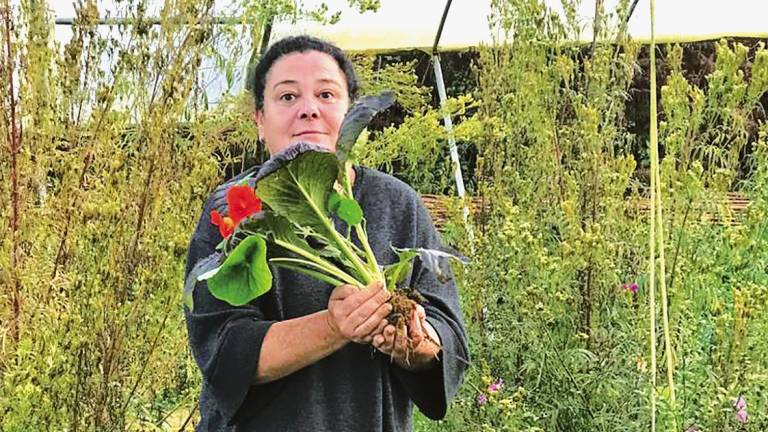 en sus manos Carmen sostiene komatsuna roja, espinaca japonesa, y hojas y flores de capuchina, cultivos de Leiriñas de Uz. Foto: Gallego.