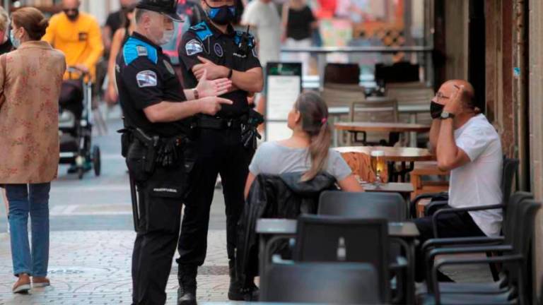 Agentes de policía explican la normativa a dos consumidores de un bar. Foto: ECG