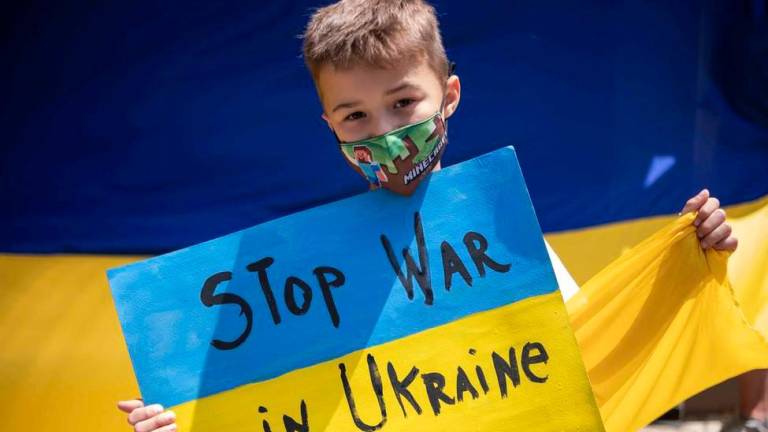 gestión humanitaria. Un niño sostiene un letrero que pide el fin de la guerra. Foto: Efe