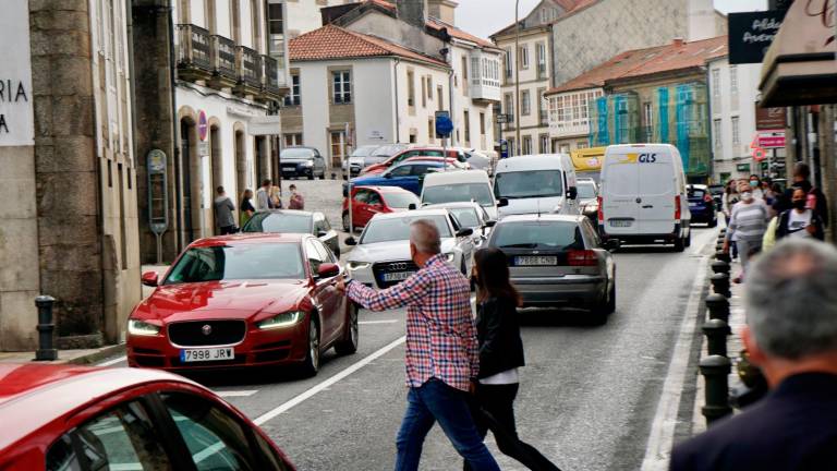 Peatones atraviesan Virxe da Cerca por el medio de la calzada, congestionada por el tráfico de automóviles. Foto: ECG
