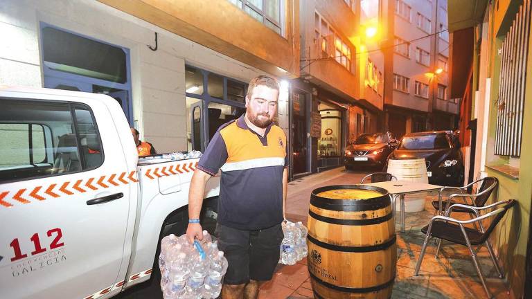 Voluntario de Protección Civil repartiendo agua embotellada en Malpica, debido a que está prohibido consumirla de la red desde el día 13. Foto: C. M.