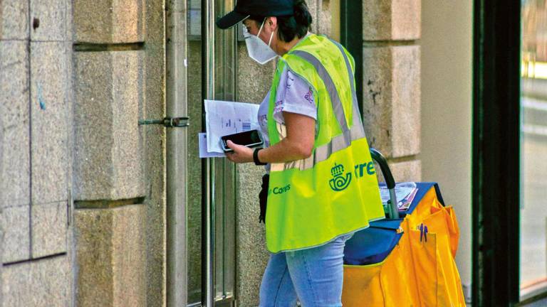 desigualdad. Una empleada de Correos reparte la correspondencia en un portal de A Coruña. Foto: Angy A.E.
