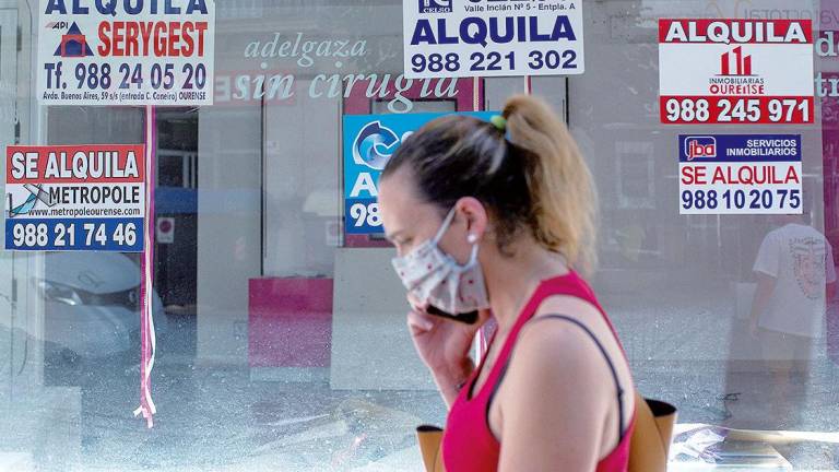 Una mujer pasa por delante de un local comercial con carteles de ‘se alquila’, en Ourense. Foto: Brais Lorenzo 