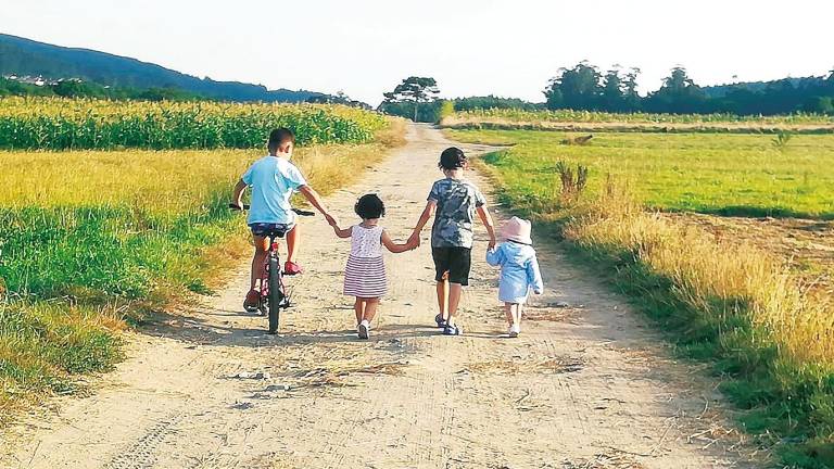 Nenos e nenas desfrutando dun plácido paseo a pé e en bicicleta por un camiño. Foto: Veciñanza de Muxía