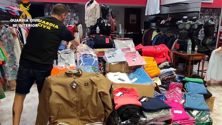 Un agente de la Guardia Civil coloca algunas de las prendas incautadas en el establecimiento situado en O Milladoiro