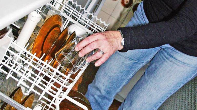 Un hombre retirando un vaso de su lavavajillas tras el proceso de lavado. Foto: E.P.