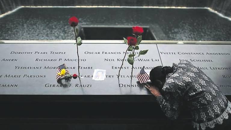 Una mujer se inclina sobre los nombres de las víctimas del 11-S en la fuente conmemorativa en Nueva York.