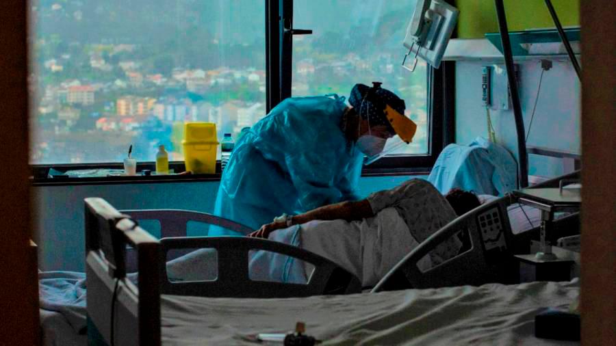 cuidados vitales. Una profesional sanitaria atiende a un paciente ingresado por coronavirus en un centro hospitalario gallego. Foto: Brais Lorenzo 