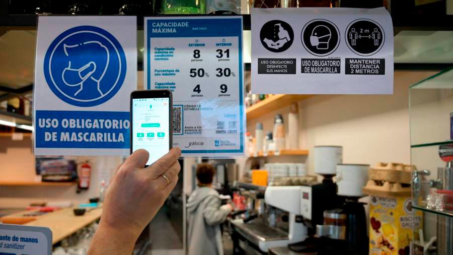 Una persona toma una foto para captar el código QR en la puerta de un restaurante en A Coruña, Galicia (España). Foto: M. Dylan
