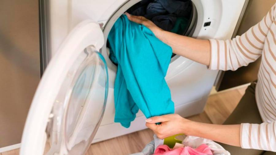 Una mujer sacando las prendas de la colada tras poner una lavadora. Foto: Gallego