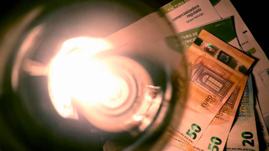 Bombilla sobre billetes y facturas de la electricidad