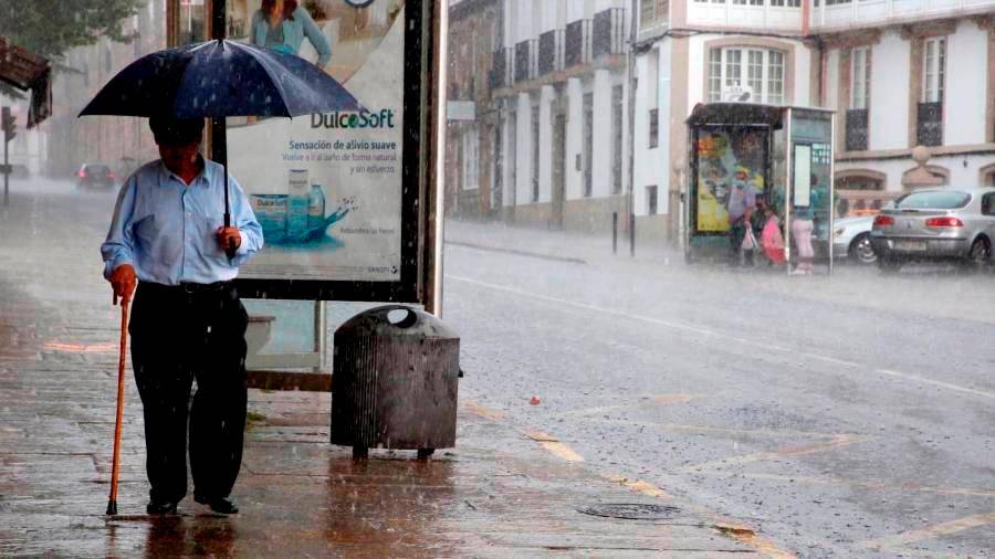 Un hombre camina con su paraguas bajo la lluvia en Santiago de Compostela. Foto: Gallego