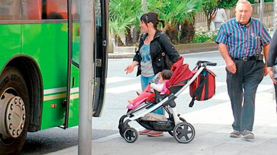 Una mujer intentando entrar a un autobús urbano con un carrito de bebé. Foto: Gallego