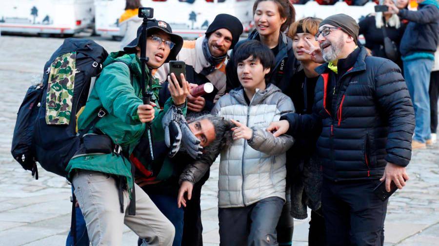 Un grupo de peregrinos, entre ellos varios coreanos, se sacan una fotografía en el Obradoiro. Foto: A. Hernández