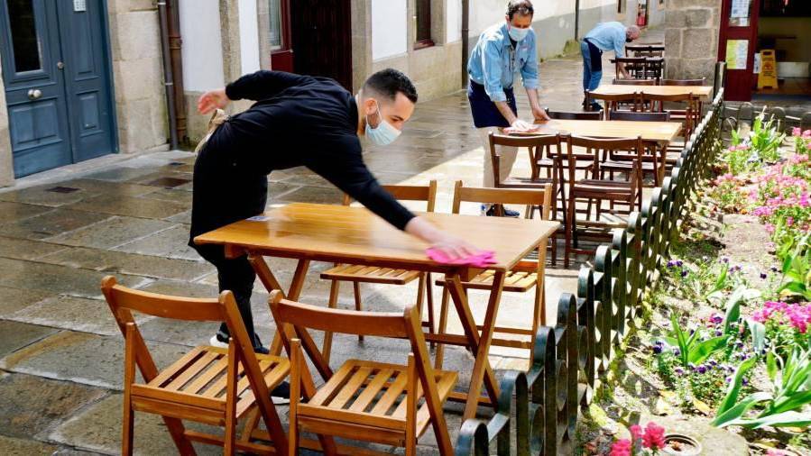 Na foto de arquivo, camareiros preparando as mesas nunha terraza da Rúa da Raíña, en Santiago. FERNANDO BLANCO