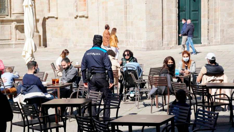 restricciones. Terrazas con clientes tomando algo en Santiago mientras la Policía Local realiza un control para detectar posibles incumplimientos. Foto: F. Blanco 