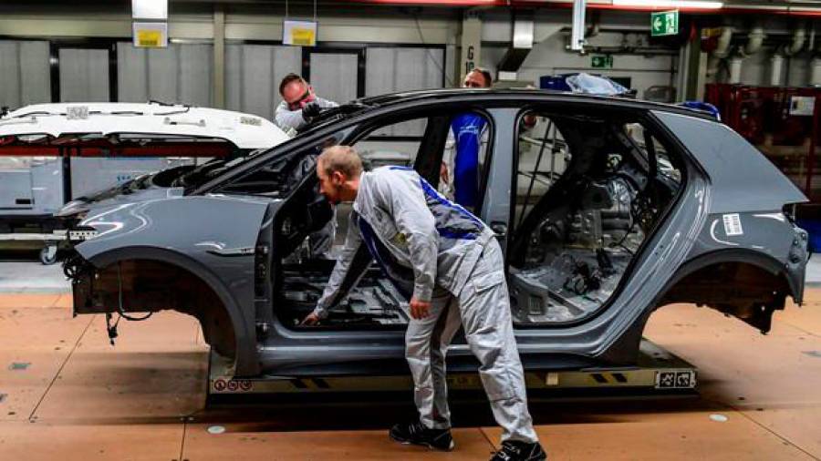 COCHES. Empleados de una fábrica alemana de Volkswagen trabajando en la cadena de montaje. Foto: EFE