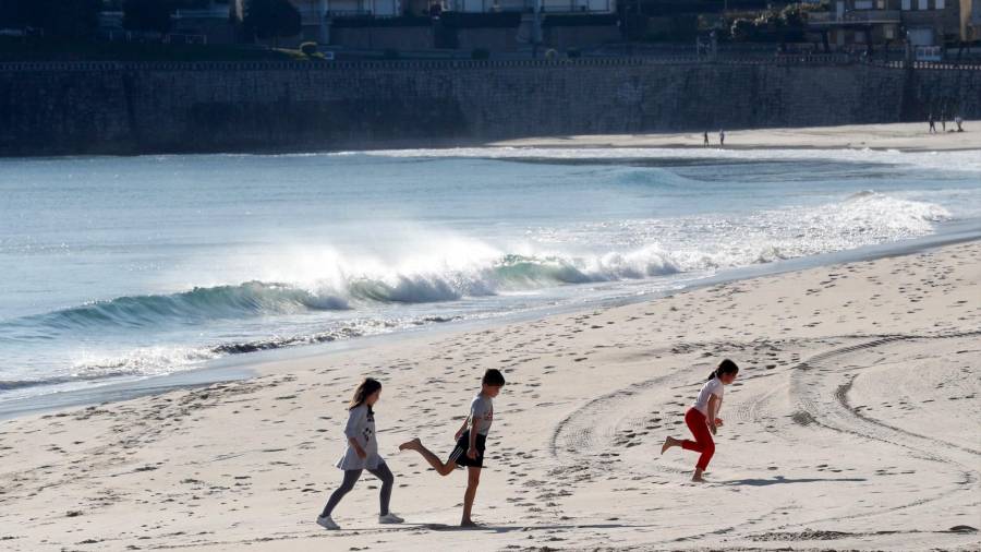 vacaciones. Tres niños juegan con la arena por la playa de Silgar (Sanxenxo). Foto: Lavandeira Jr (Efe)