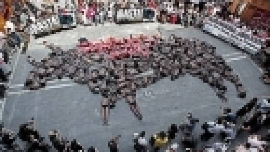Activistas forman la figura de un toro muerto para mostrar su oposición a los encierros
