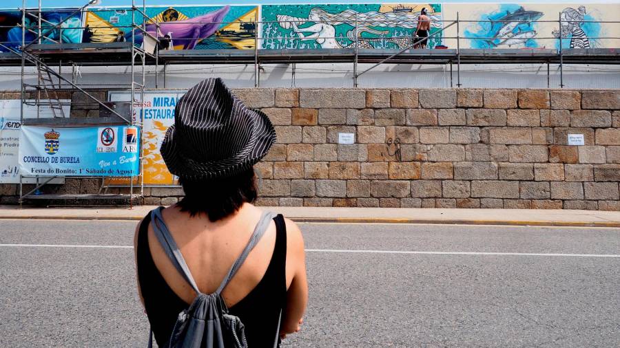 Una mujer observando las propuestas de los participantes en la edición de hace dos años del Certame Internacional de Pintura Mural Amarte de Burela. Foto: Eliseo Trigo/Efe