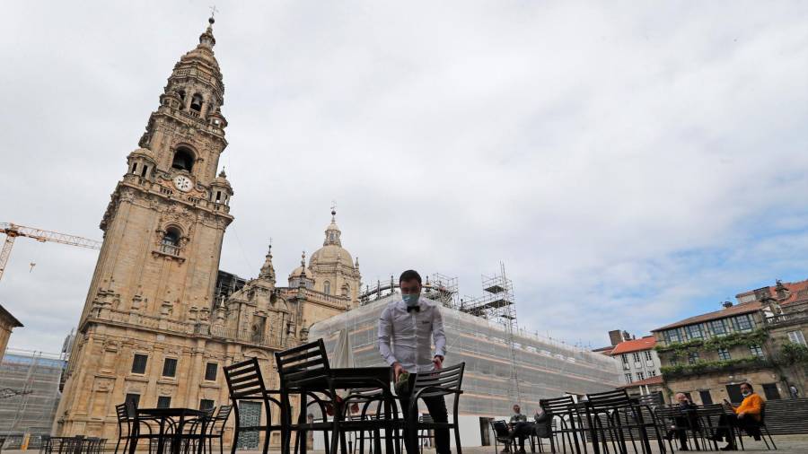 TURISMO. Un camarero monta la terraza en la Plaza de A Quintana, ante la Catedral de Santiago, en el primer día de la fase 1 de la desescalada en Galicia. Foto: EFE / J. Lavandeira