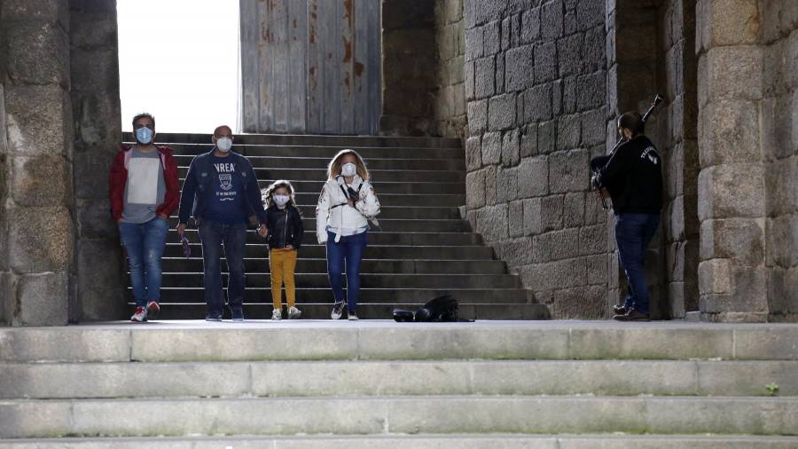 Una familia con mascarillas pasa por el arco de Xelmírez, en Santiago, el domingo. ANTONIO HERNÁNDEZ
