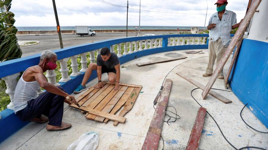 LA HABANA (CUBA), 24/08/2020.- Tres hombres aseguran las ventana de una casa ante la proximidad de la tormenta Laura, el lunes, en La Habana (Cuba). EFE/ Yander Zamora