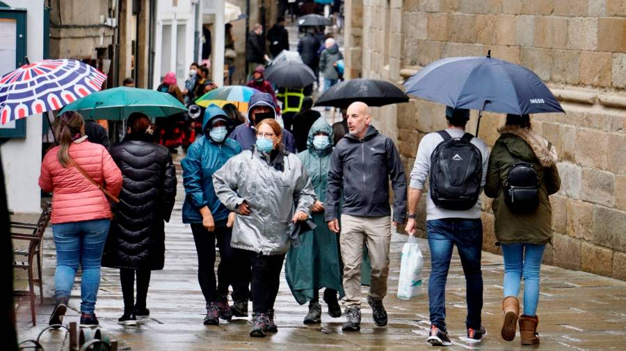 Turistas paseando polo casco histórico de Santiago nun día de choiva no mes de novembro. Foto: Fernando Blanco.