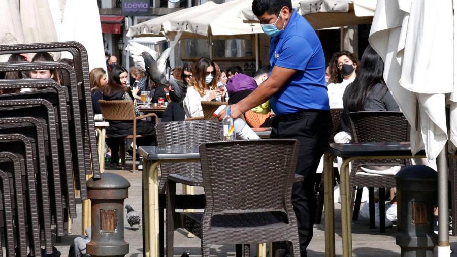 Un camarero desinfecta las mesas de una terraza, en Santiago (Foto: Antonio Hernández)