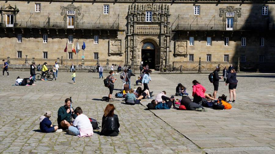 Peregrinos y visitantes sentados en la plaza del Obradoiro disfrutando del sol. Foto: F. Blanco