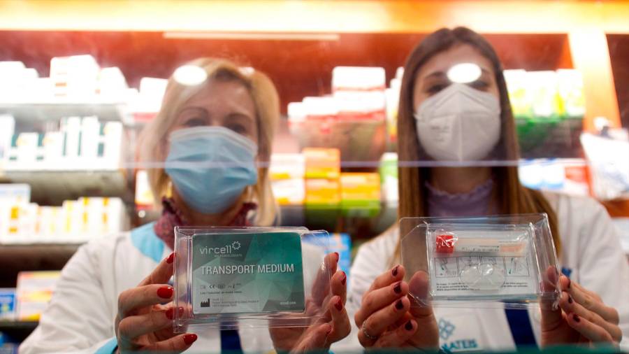 Dos farmacéuticas posan con el kit que se distribuye para recoger muestras de saliva (Foto: EFE/Salvador Sas)